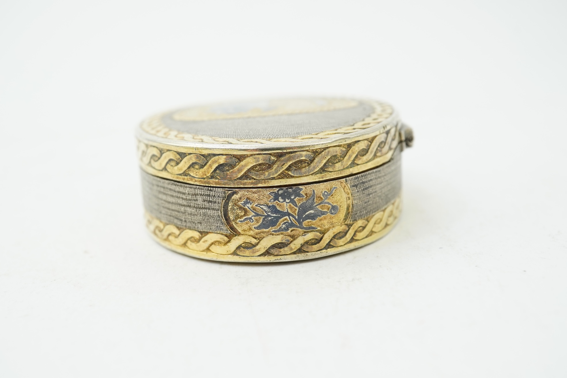 A 19th century Swiss? parcel gilt white metal oval snuff box with hinged cover